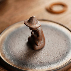 Ceramic meditating figure detail on teapot lid, artisan crafted