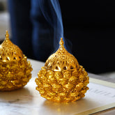 Gold Pine Cone Mini Incense Burner - Two golden units with blue smoke, dark bokeh, ritual decor