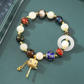 Liuli Glass Prayer Wheel Bracelet – Flat lay on teal surface showing cloisonne beads and jade ring