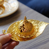 Tibetan Gold Leaf Coaster Incense Burner – Gold dome lid held in hand with filigree cutouts on wood table, brass incense burner