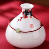 Hetian Jade Lotus Red String Bracelet - Single bracelet on ceramic vase with plum blossom art, red backdrop, fortune