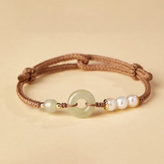 Hetian Jade Pearl Peace Buckle Bracelet – celadon jade bi disc with pearls and gold accents on brown cord, cream background studio shot