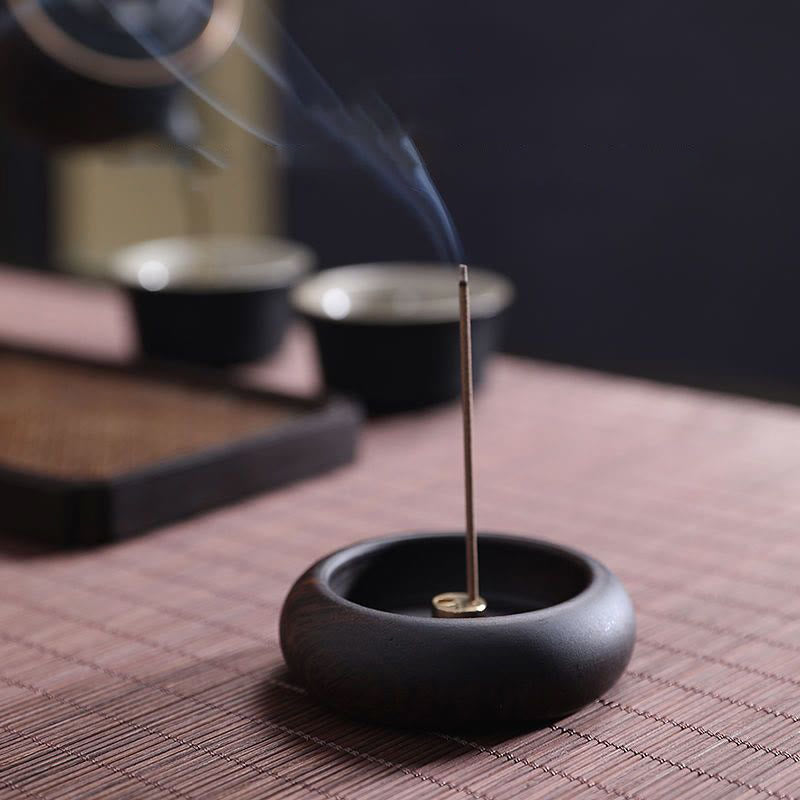 Stick incense burner with brass insert and smoke on woven mat, healing