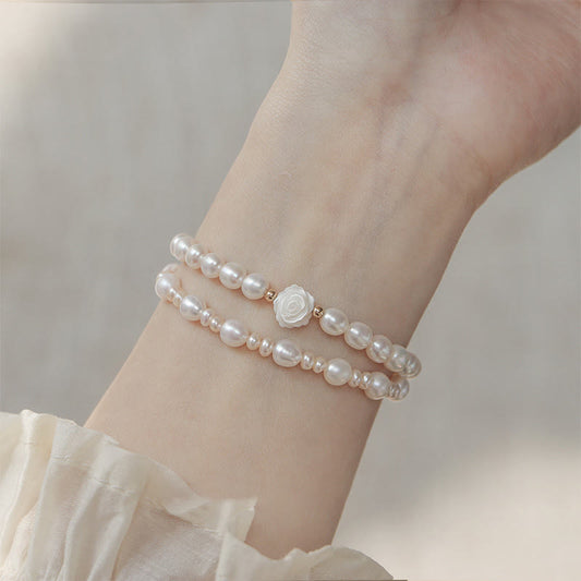 Natural Pearl Sincerity Bracelet – White pearl beads on silver chain bracelet with rose gold accents, pinkish-purple clematis flower and blurred pink background