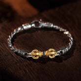 Vajra Bracelet – silver chain bracelet with gold vajra centerpiece and blue gems on dark wood surface