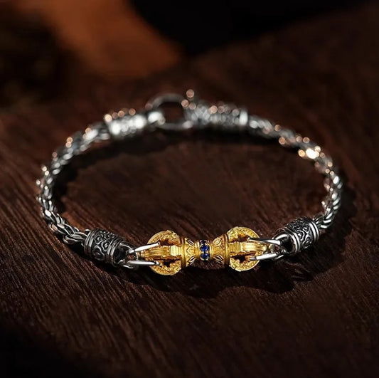 Vajra Bracelet – silver chain bracelet with gold vajra centerpiece and blue gems on dark wood surface