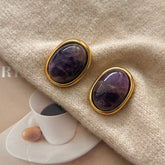 Amethyst Stud Earrings – oval purple amethyst cabochons in gold bezel setting on cream knit sweater with magazine props, crystal earrings