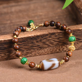 Dzi Rosewood Bracelet – Rosewood beads with Tibetan dzi centerpiece on wooden plank, green accent stones