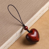 Rosewood Heart Keychain – polished red heart pendant with silk cord on vintage book, wood grain detail