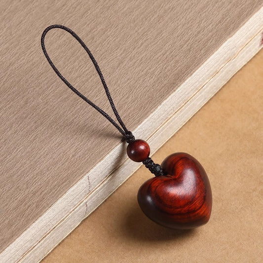 Rosewood Heart Keychain – polished red heart pendant with silk cord on vintage book, wood grain detail