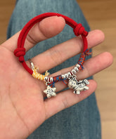 Horse Red String Bracelet – Red cord with silver horse charm and fortune star, hand held over jeans, zodiac