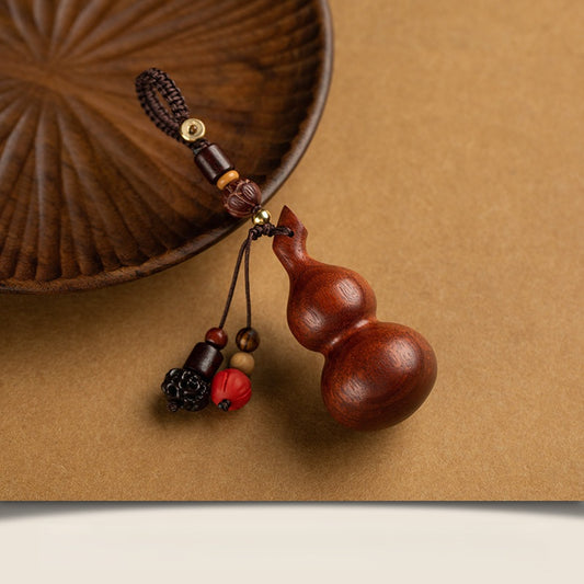 Sandalwood Gourd Keychain – reddish gourd with beaded tassels beside carved wooden plate