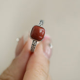 Red Agate Openwork Ring – square red agate sugar cube held between fingers on beige background, red agate ring