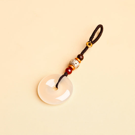 Jade Keychain Pendant – White jade donut pendant with braided rope and bodhi beads on beige background, feng shui