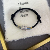 Black String Bracelet – single black cord with silver bead and multicolor weave on white fabric