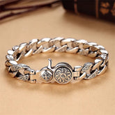 Om Mani Padme Hum Dorje Vajra Copper Bracelet – Silver curb chain with engraved links and ornate floral clasp, warm beige leather with blurred books, side angle
