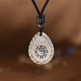 Yin Yang Bagua Water Drop Necklace – Silver teardrop pendant with yin-yang and bagua symbols on black cord with cloud-engraved beads, brown background