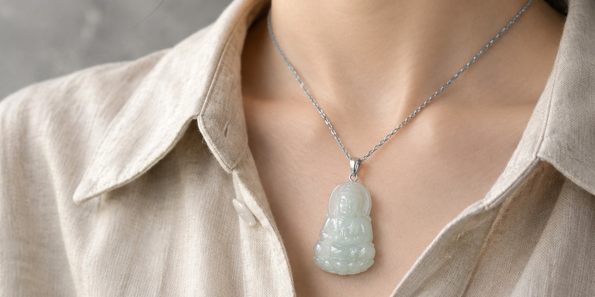 Carved jade Buddha pendant on a silver chain resting against an oatmeal linen shirt collar