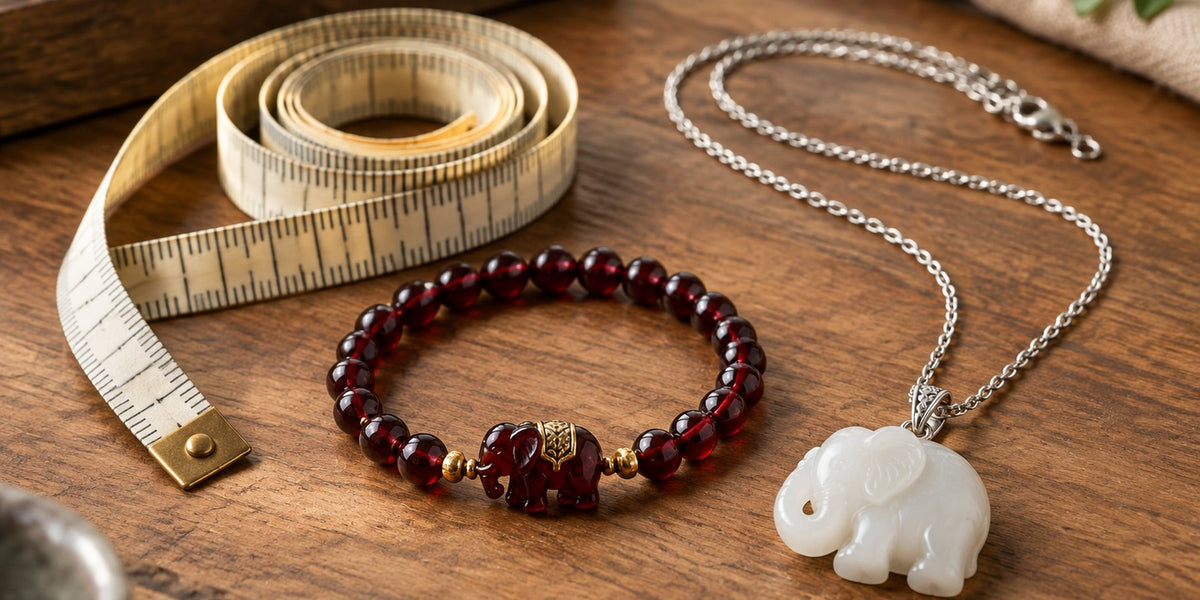 Tape measure beside a garnet beaded bracelet and a white jade elephant pendant