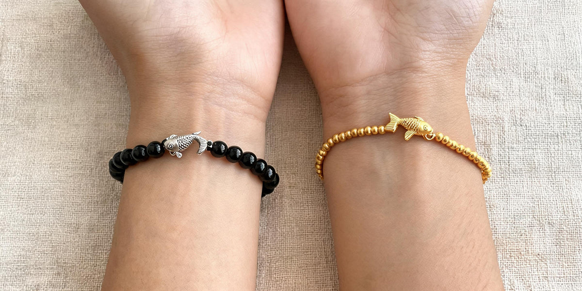 Black obsidian koi bracelet on the left wrist and gold koi bracelet on the right wrist