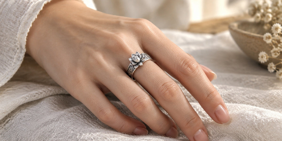 Sterling silver lotus ring with engraved floral band worn on the index finger