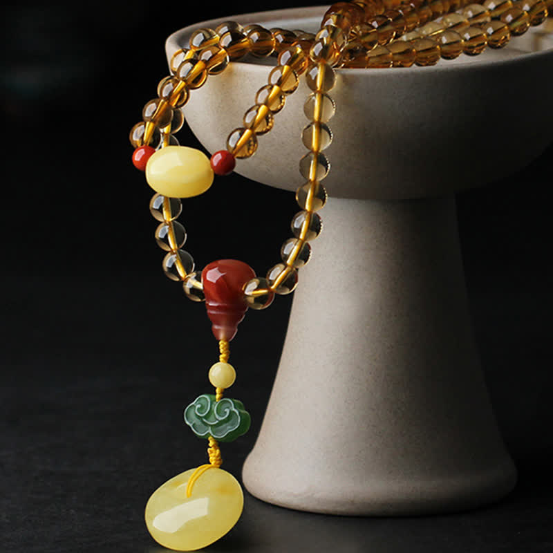 Citrine Mala Bracelet – Citrine beads with amber pendant on white ceramic pedestal, dark bg