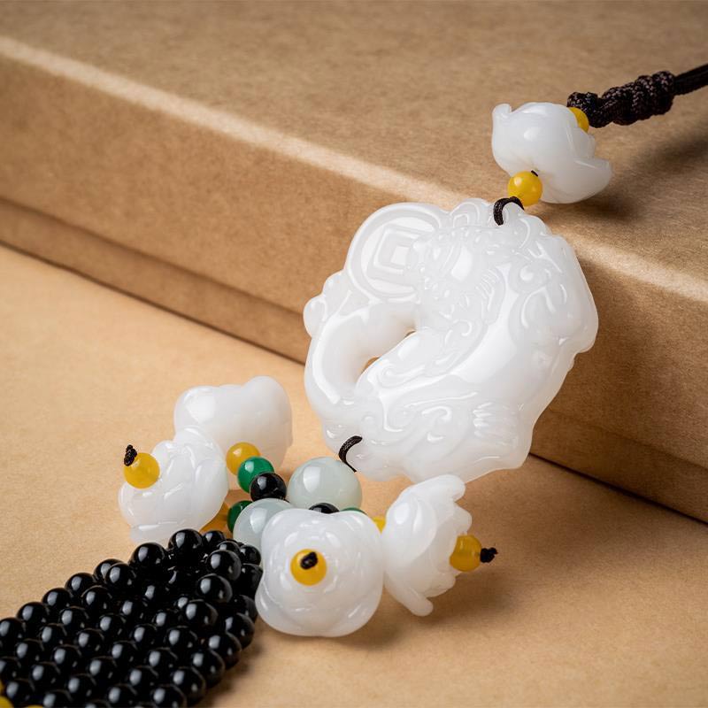 FengShui Jade PiXiu Car Pendant – white jade PiXiu carving closeup on book, intricate detail lotus beads, good luck