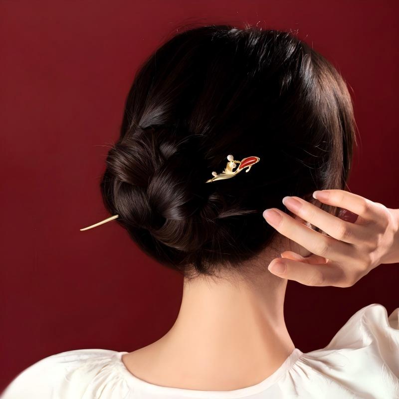 Koi Hairpin – styled in a low bun with hand touching hair, maroon studio background, daily wear