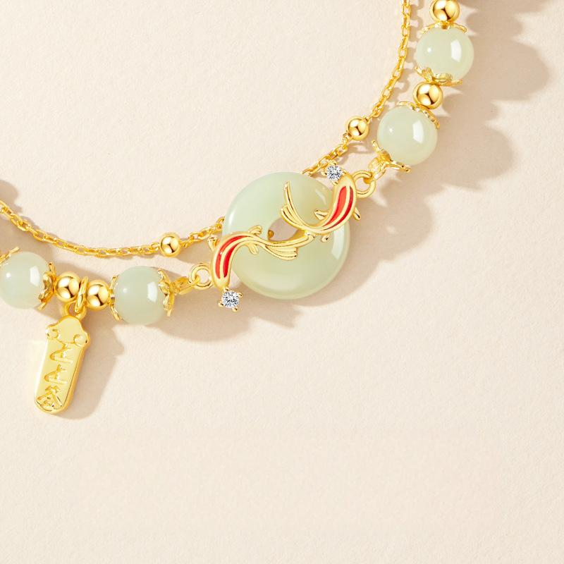 Hetian Jade Bracelet – Close-up of pale green jade beads gold koi fish peace button with crystal details, women luxury
