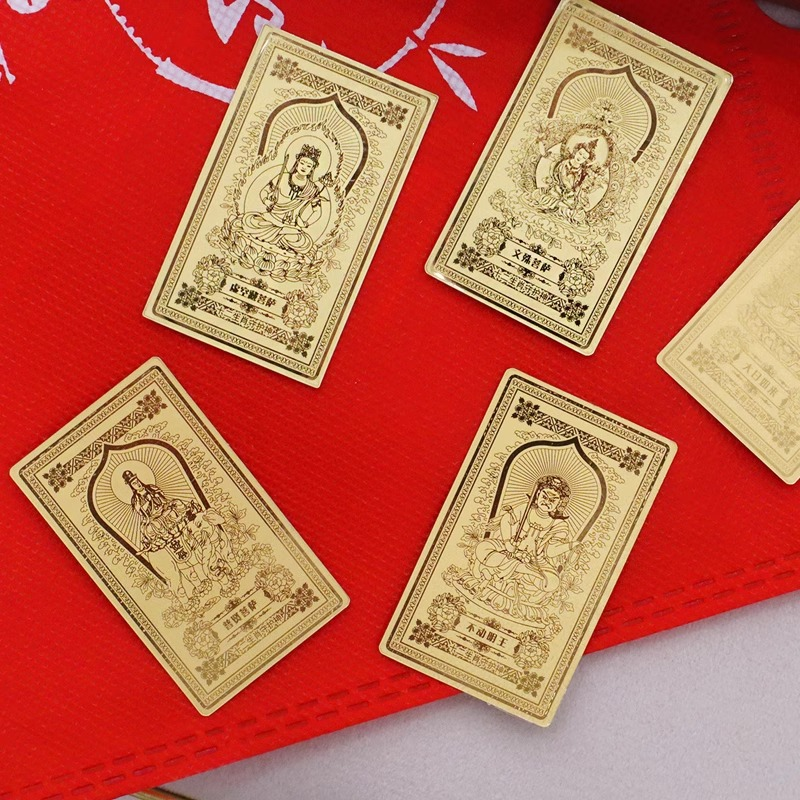Guardian Gods Gold Foil Phone Sticker – four assorted deity gold foil stickers laid on red textured surface, including Akasagarbha, Manjushri and others, intricate embossed gold patterns, collection flat lay
