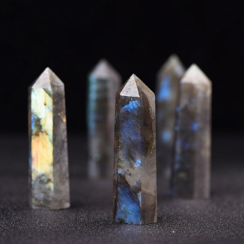 Group of natural labradorite crystal pillars with iridescent blue flash, black background, chakra balance tower points