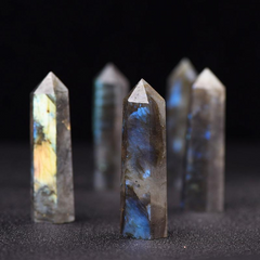 Group of natural labradorite crystal pillars with iridescent blue flash, black background, chakra balance tower points
