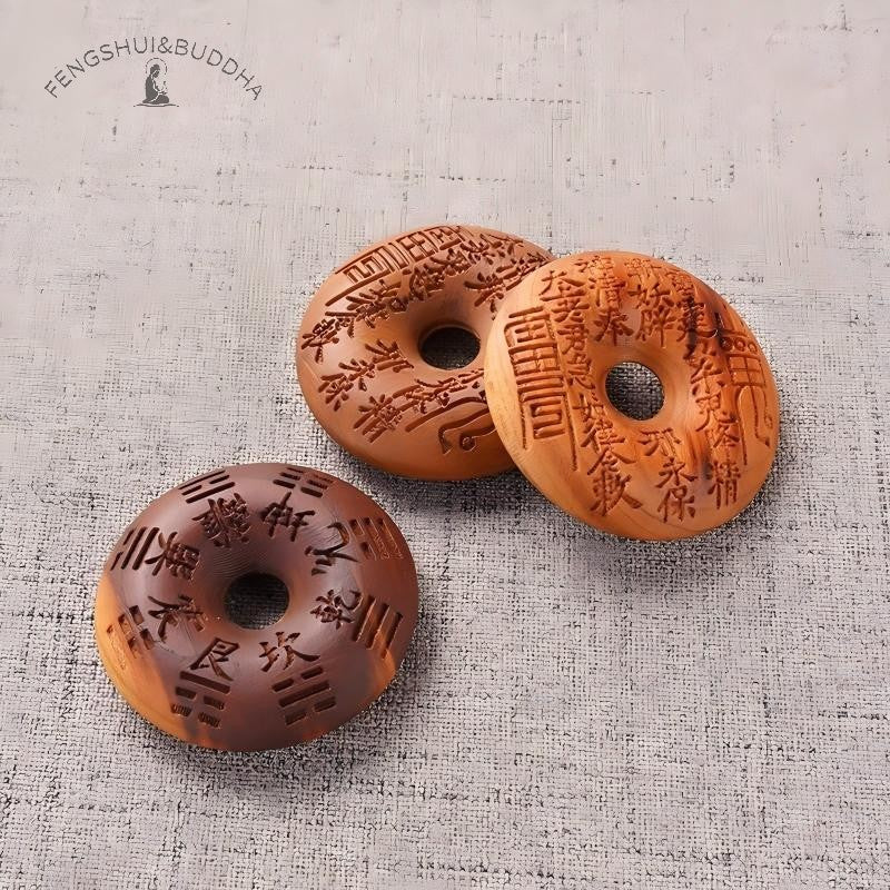 Peach Wood Bagua Coin – three coins stacked displaying detailed spell and trigram carvings, textured grey cloth, Chinese talisman