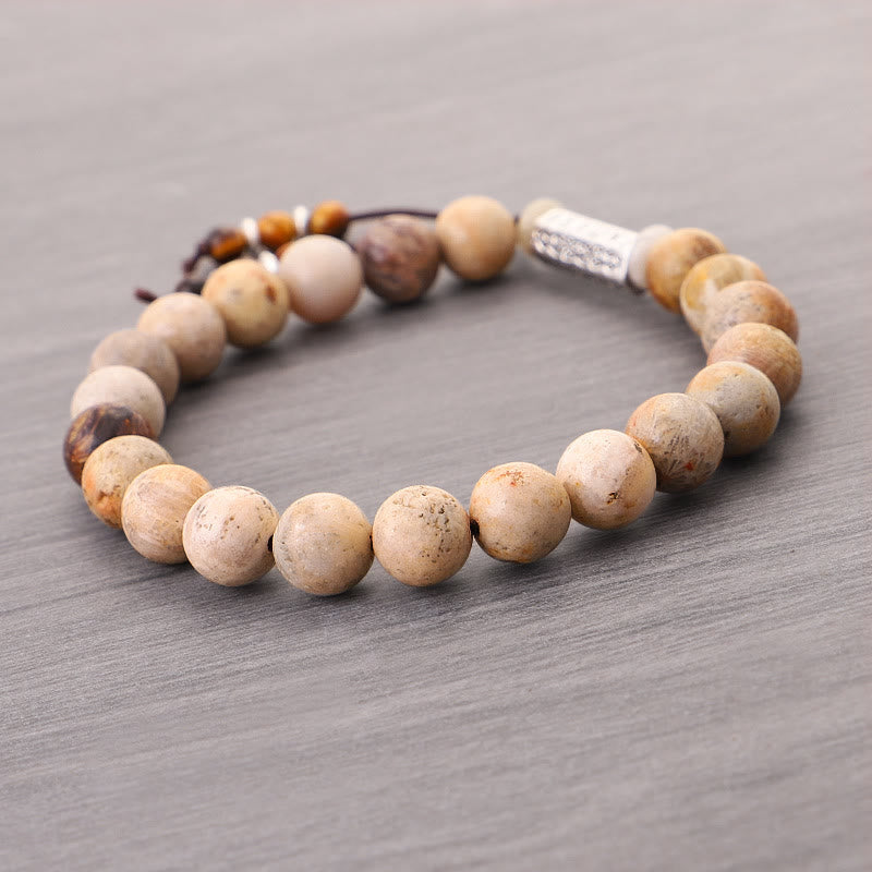 Weathered Stone Om Mani Padme Hum Bracelet – fossilized stone beads with adjustable cord closure on gray wood, men’s mala