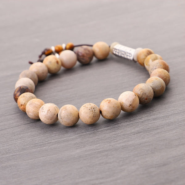 Weathered Stone Om Mani Padme Hum Bracelet – fossilized stone beads with adjustable cord closure on gray wood, men’s mala