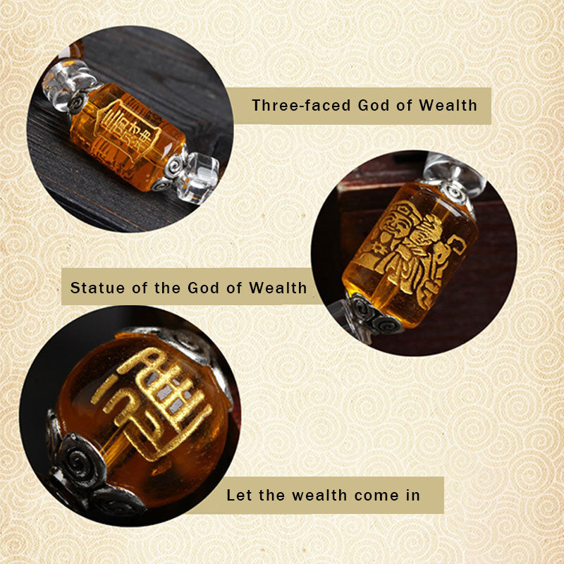 Three carved amber barrel beads showing Three-faced God of Wealth, Wealth deity statue and fortune character designs with gold inlay and silver end caps on traditional pattern background