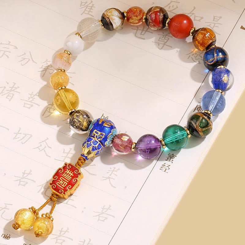 Tibetan Liuli Wrist Mala – 18 multicolor beads displayed on Buddhist scripture with red fortune charm