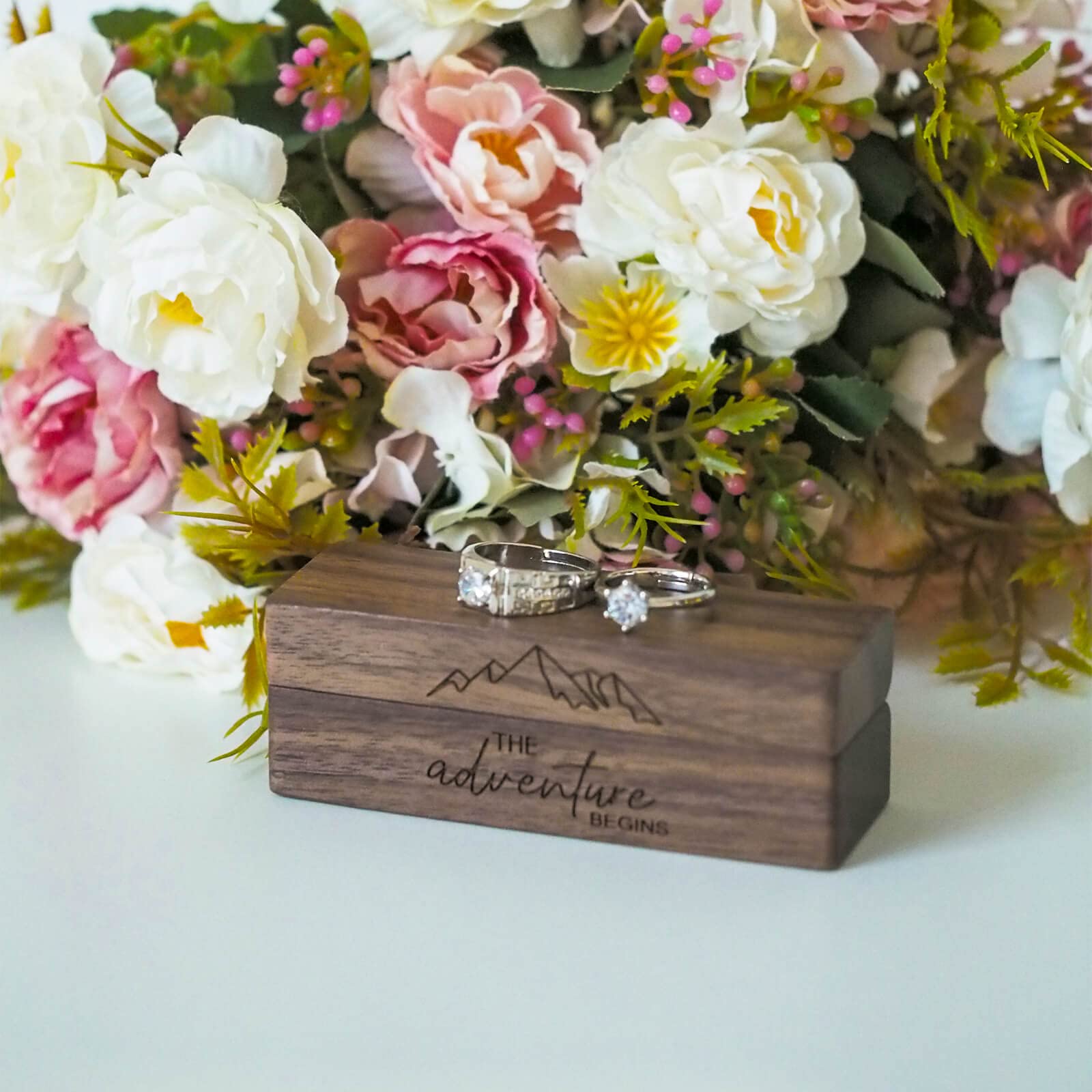 Engraved Walnut Ring Box – his and hers rings on box with mountain engraving and floral backdrop, rustic wedding