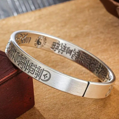 Antique Tai Chi Bracelet – side view of silver cuff with etched charms next to dark wood, energy balance