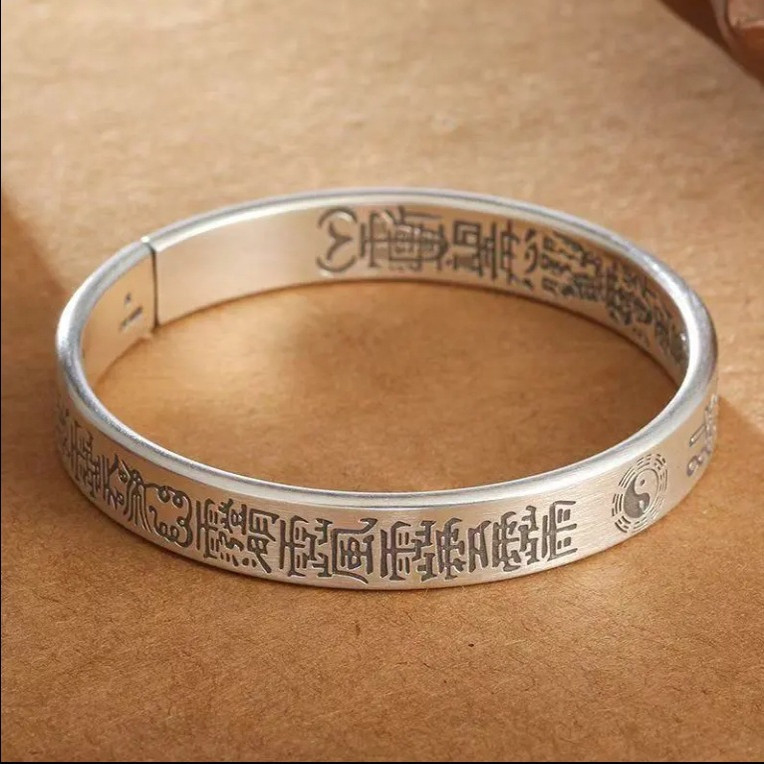 Antique Tai Chi Bracelet – flat lay on tan surface showing full engraved circle with Tai Chi, protection amulet