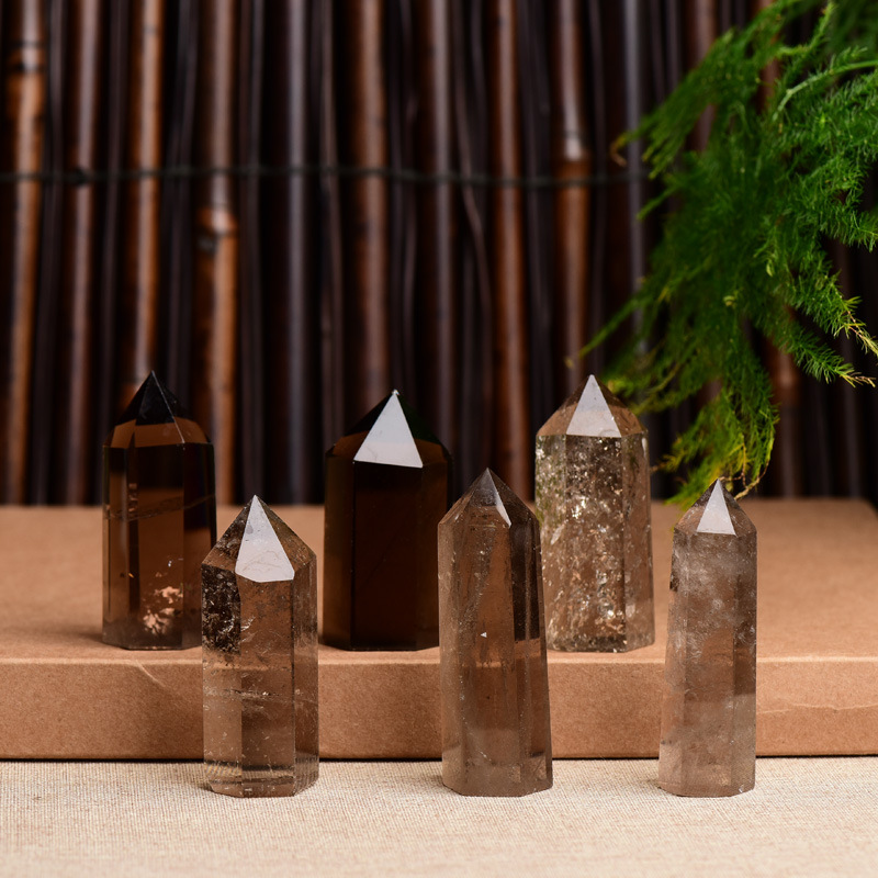 Six natural smoky quartz crystal points on tiered brown stand, bamboo and greenery background, polished healing towers