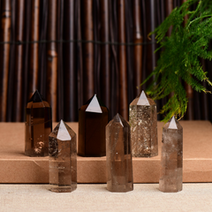 Six natural smoky quartz crystal points on tiered brown stand, bamboo and greenery background, polished healing towers