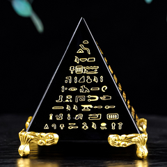 Close-up front view of black obsidian pyramid with gold Egyptian hieroglyphs, gold decorative base, dark background, spiritual energy pyramid