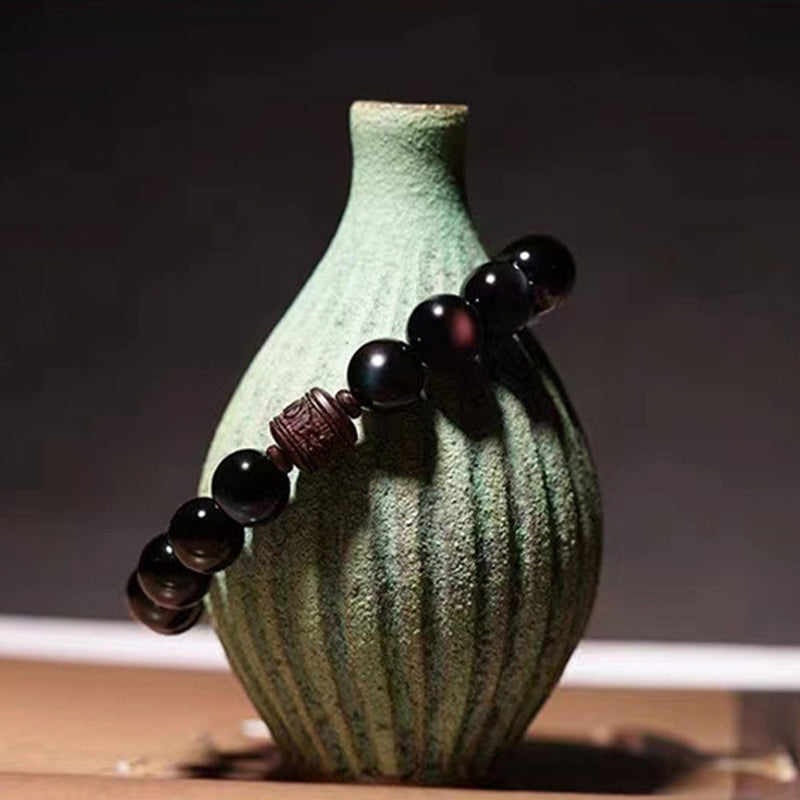 Gold Sheen & Rainbow Obsidian Fu Bracelet – draped over green ceramic vase, obsidian bead bracelet