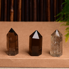 Three natural smoky quartz crystal points on brown surface, varying transparency and inclusions, grounding stone towers