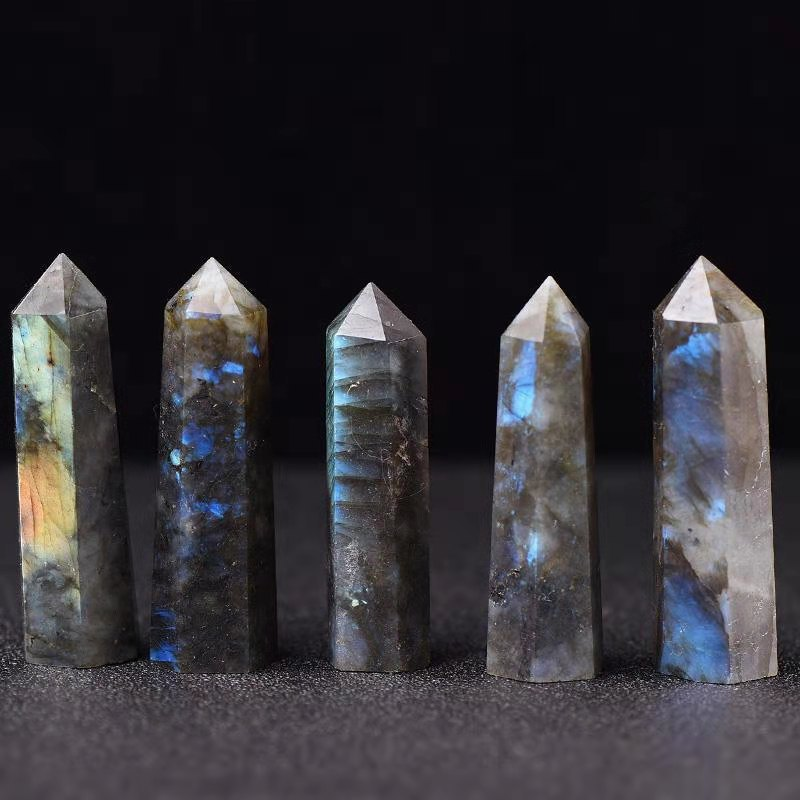 Row of five natural labradorite crystal pillar towers, black background, polished healing stones with blue and green flash