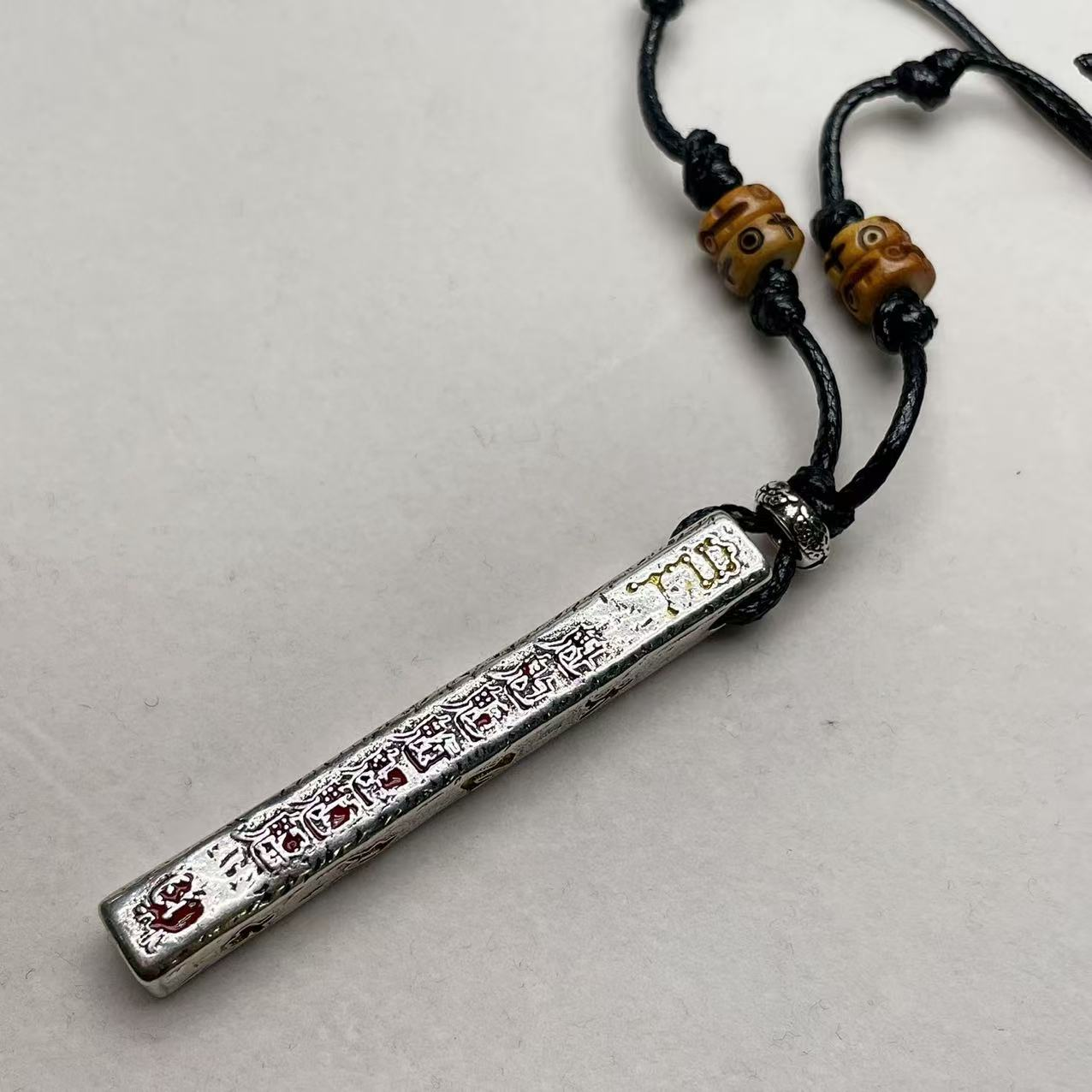 Tian Peng Chi Pendant – silver rectangular ruler pendant on black cord with wooden beads, gray backdrop, engraved talisman text, protection necklace