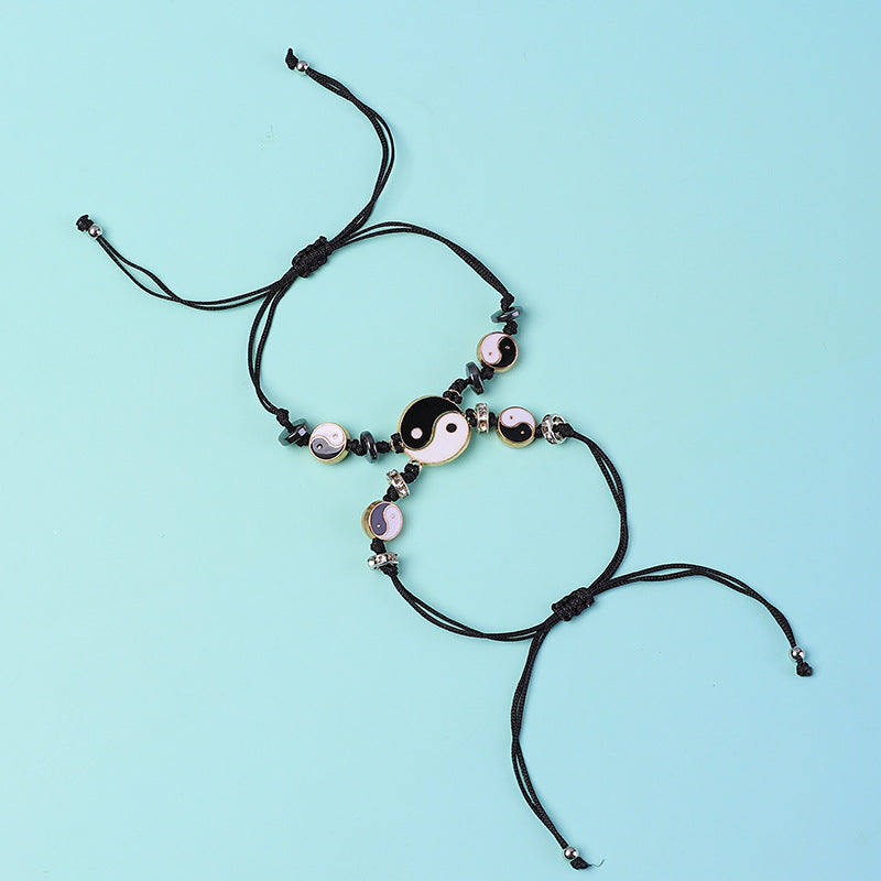 Yin Yang Hematite Bracelet - Black cord pair with large yin-yang charms on blue background