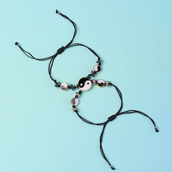 Yin Yang Hematite Bracelet - Black cord pair with large yin-yang charms on blue background