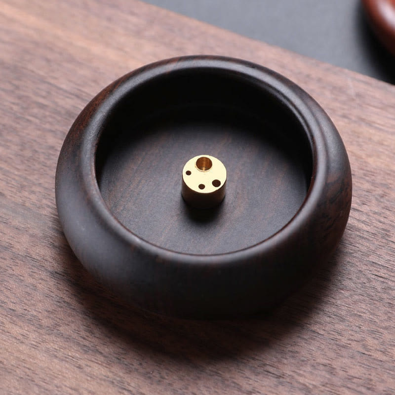 Ebony wood incense bowl with multi-hole brass insert on light wood, mindful